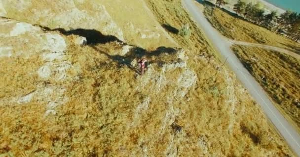 Orbital radial flight around young hiking man standing on top of the cliff. Looks away. — Stock Video