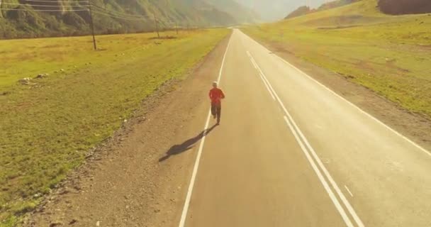 Vuelo de baja altitud frente al deportista en el camino perfecto de asfalto — Vídeo de stock