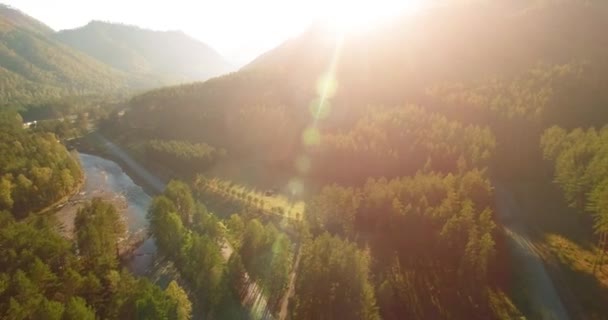 Volo a mezz'aria sul fiume fresco di montagna e prato al mattino d'estate soleggiato. Strada sterrata rurale sotto. — Video Stock