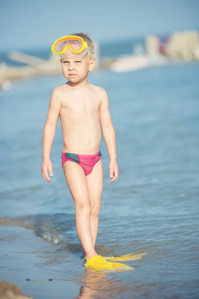 Lindo niño pequeño con máscara y aletas para bucear en la playa tropical de arena . — Foto de Stock