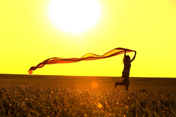 Молодая женщина бежит по сельской дороге на закате в летнем поле. Свободный образ жизни — стоковое фото