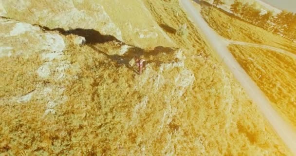 Orbital radial flight around young hiking man standing on top of the cliff. Looks away. — Stock Video