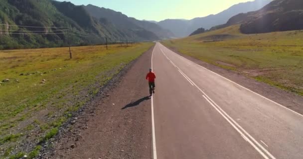 Vlucht van de lage hoogte achter van sportieve man op perfecte asfaltweg — Stockvideo