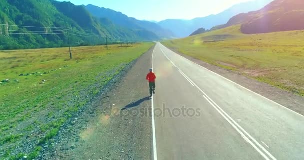 Voo de baixa altitude atrás de homem desportivo na estrada de asfalto perfeito — Vídeo de Stock