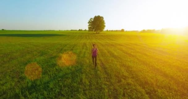 UHD 4K aerial view. Low altitude flight in front of sporty woman at rural field — Stock Video