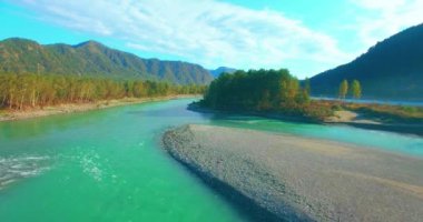 4k UHD hava görüntüsü. Güneşli yaz sabahında taze soğuk dağ nehri üzerinde alçak uçuş. Horisont 'ta yeşil ağaçlar ve güneş ışınları