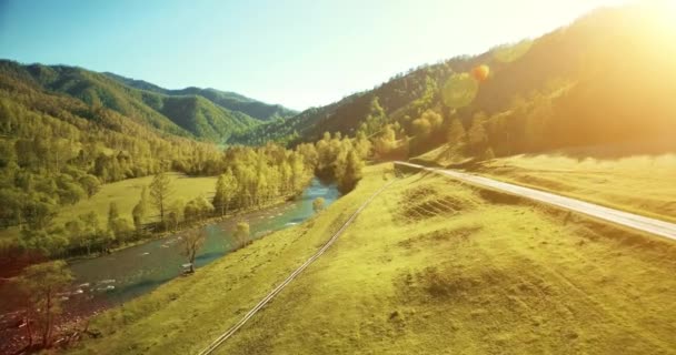 UHD 4K vista aérea. Vôo baixo sobre o rio frio fresco da montanha, o prado e a estrada na manhã ensolarada do verão . — Vídeo de Stock