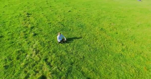 Uhd 4k légifelvételek. Alacsony Orbitális repülés alatt ül a zöld fű, notebook pad mező üzletember — Stock videók