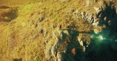 Genç yürüyüş adam uçurumun üstünde ayakta çevresinde yörünge Radyal uçuş. Uzakta görünüyor.