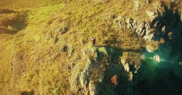 Orbitális sugárirányú repülés körül gyalogos fiatalember, egy szikla tetején áll. Úgy néz ki, el. — Stock videók