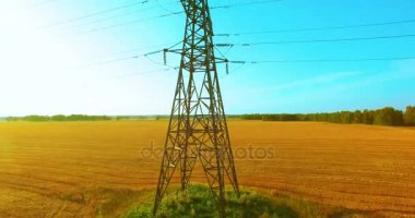 Yüksek voltajlı elektrik kulesi ve yeşil ve sarı alandaki elektrik hatları yakınında dikey hareket.