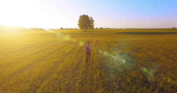 UHD 4K aerial view. Low altitude flight in front of sporty woman at rural field — Stock Video