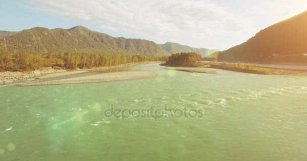 4k UHD aerial view. Low flight over fresh cold mountain river at sunny summer morning. Green trees and sun rays on horisont — Stock Video