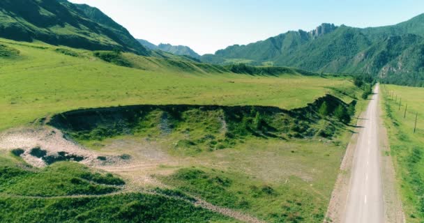 Aerial rural mountain road and meadow at sunny summer morning. Asphalt highway and river. — Stock Video