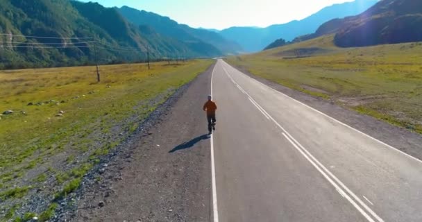 Vol à basse altitude derrière un homme sportif sur une route asphaltée parfaite — Video