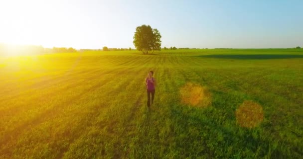 UHD 4K aerial view. Low altitude flight in front of sporty woman at rural field — Stock Video