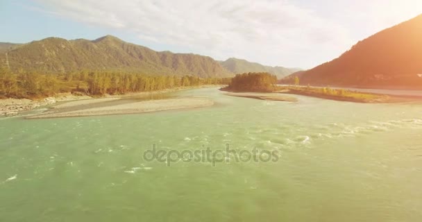 4k UHD vista aérea. Vôo baixo sobre o rio frio fresco da montanha na manhã ensolarada do verão. Árvores verdes e raios solares em horisont — Vídeo de Stock