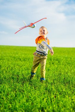 Oyuncak uçak mavi yaz gökyüzü ve yeşil alan arka plan karşı oynamaktan mutlu çocuk.