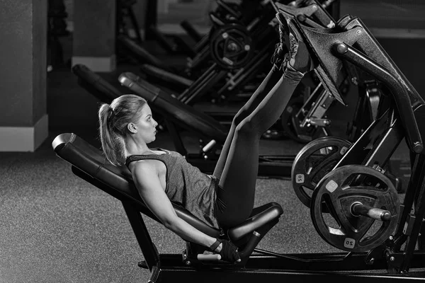 Mujer deportiva usando máquina de prensa de pesas para las piernas. Gimnasio . — Foto de Stock