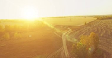 UHD 4K hava görüntüsü. Sarı kırsal alan ve toprak yol üzerinde orta-uçuş