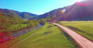 Güneşli yaz sabahında taze dağ nehri ve çayır üzerinde uçuşun ortasında. Aşağıdaki kırsal toprak yol.