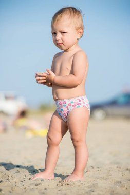 Şirin Bebek denize yakın kum plajındaki oyuncaklar ile oynama.