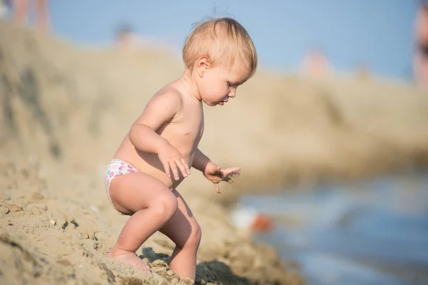 Lindo bebé jugando con juguetes en la playa de arena cerca del mar . —  Fotos de Stock