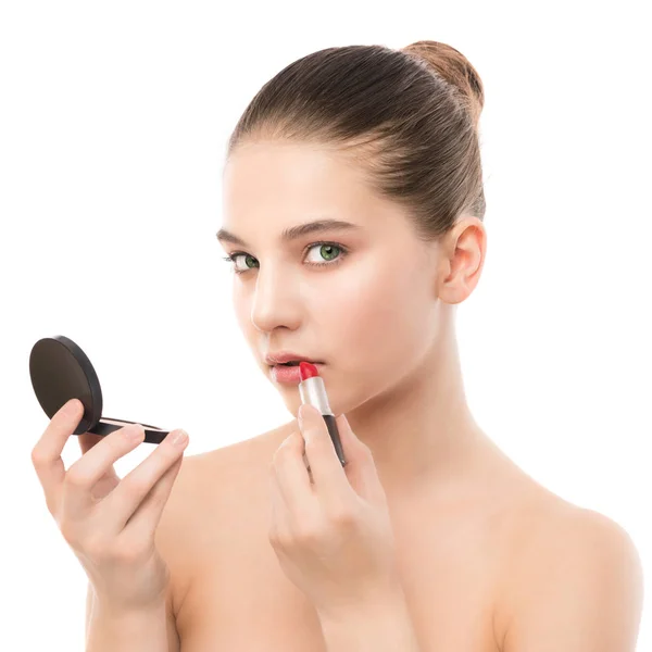 Jonge brunette vrouw met perfect schoon gezicht lippenstift met behulp van spiegel toe te passen. Geïsoleerd op een witte. — Stockfoto
