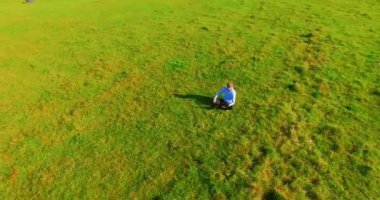 UHD 4k havadan görünümü. Defter pad ile yeşil çim sahasında oturan işadamı üzerinde düşük yörünge uçuş