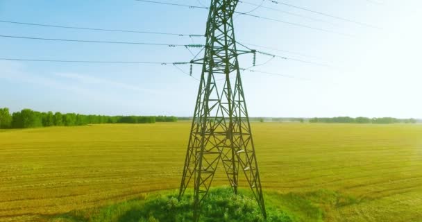 Voo de movimento vertical perto de torre de eletricidade de alta tensão e linhas de energia no campo verde e amarelo — Vídeo de Stock