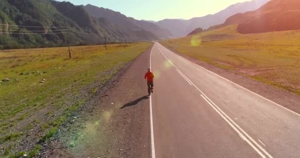Vuelo a baja altitud detrás del hombre deportivo en el camino perfecto de asfalto — Vídeo de stock