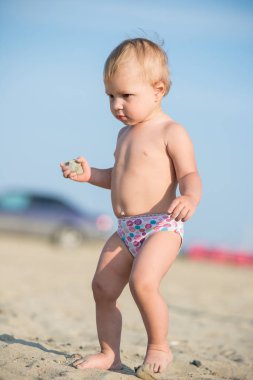 Şirin Bebek denize yakın kum plajındaki oyuncaklar ile oynama.