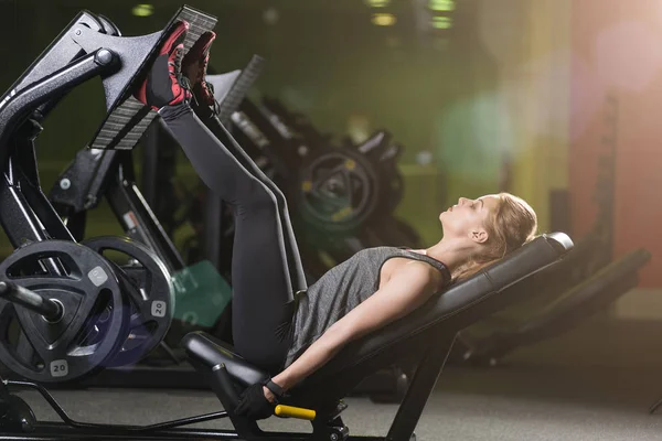 Mujer deportiva usando máquina de prensa de pesas para las piernas. Gimnasio . — Foto de Stock