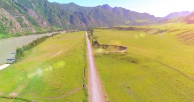 Güneşli yaz sabahında havadan kırsal dağ yolu ve çayır. Asfalt karayolu ve nehir.