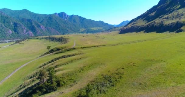 Légi vidéki hegyi út és rét napos nyári reggelen. Aszfalt autópálya és folyó. — Stock videók