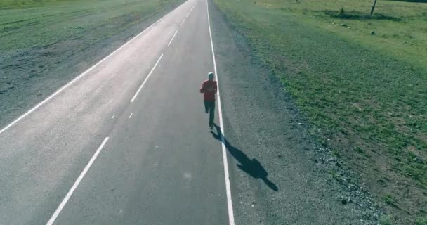Vuelo de baja altitud frente al deportista en el camino perfecto de asfalto — Vídeos de Stock