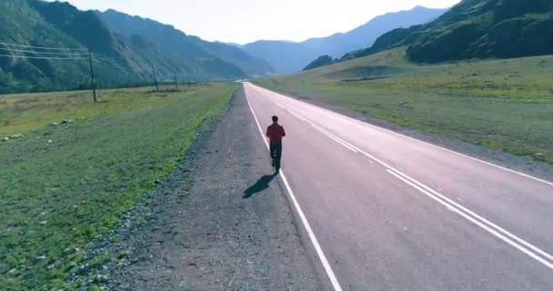 Voo de baixa altitude na frente do homem desportivo na estrada de asfalto perfeito — Vídeo de Stock