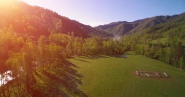 Güneşli yaz sabahında taze dağ nehri ve çayır üzerinde uçuşun ortasında. Aşağıdaki kırsal toprak yol.