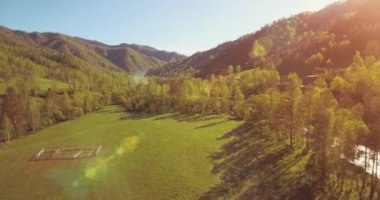 Güneşli yaz sabahında taze dağ nehri ve çayır üzerinde uçuşun ortasında. Aşağıdaki kırsal toprak yol.