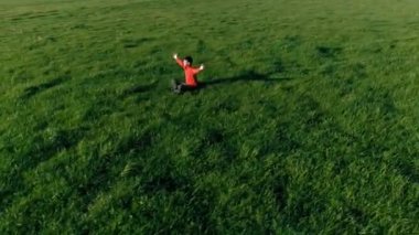 Yeşil çimlerde spor yogacısı üzerinde alçak irtifa radyal uçuş. Dağda gün batımı.