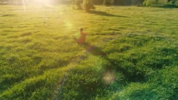 Vuelo radial de baja altitud sobre el hombre del yoga del deporte en hierba verde perfecta. Puesta de sol en montaña. — Vídeos de Stock