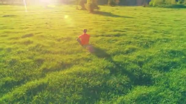 Lage hoogte radiale vlucht over sport yoga man op perfect groen gras. Zonsondergang in de bergen. — Stockvideo