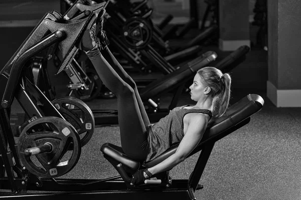 Mujer deportiva usando máquina de prensa de pesas para las piernas. Gimnasio . — Foto de Stock