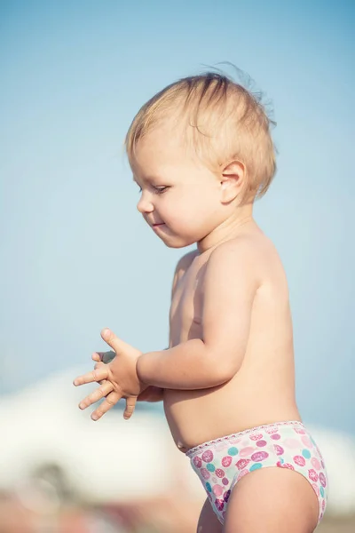 Niedliches Baby spielt mit Spielzeug am Sandstrand in Meeresnähe. — Stockfoto