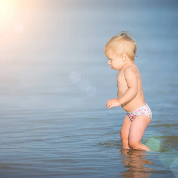 Schattige baby spelen op het zandstrand en in zeewater. — Stockfoto