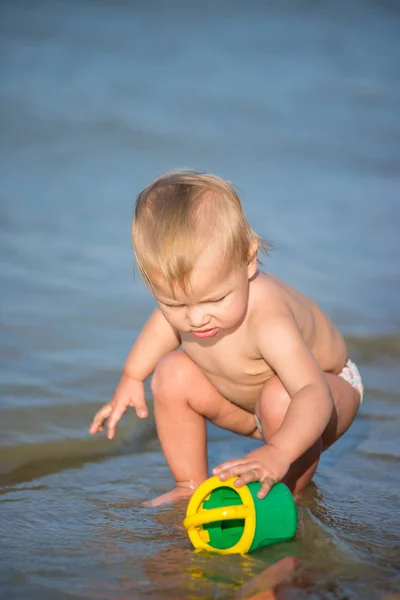 Carino bambino che gioca sulla spiaggia di sabbia e in acqua di mare . — Foto Stock