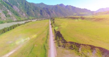 Güneşli yaz sabahında havadan kırsal dağ yolu ve çayır. Asfalt karayolu ve nehir.