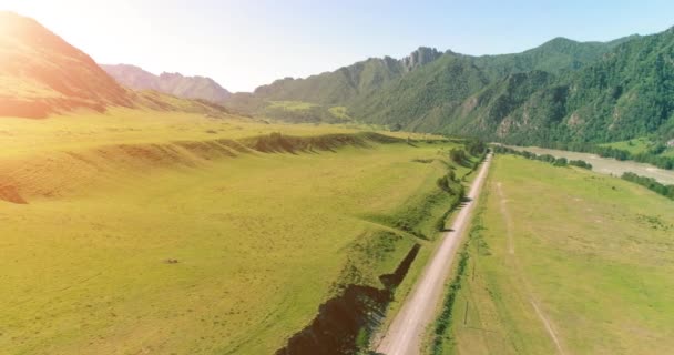 Route de montagne rurale aérienne et prairie au matin ensoleillé d'été. Asphalte autoroute et rivière. — Video