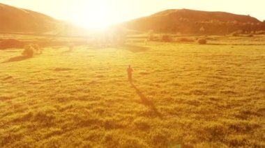 Mükemmel yeşil çayır üzerinde uçan bir sporcu. Dağda gün batımı