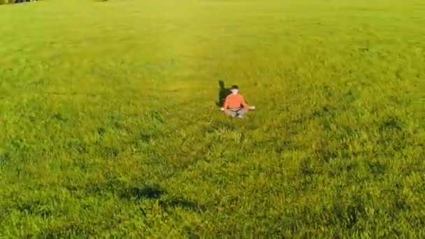 Låg höjd radiell flygning över sport yoga man på perfekt grönt gräs. Solnedgång i bergen. — Stockvideo